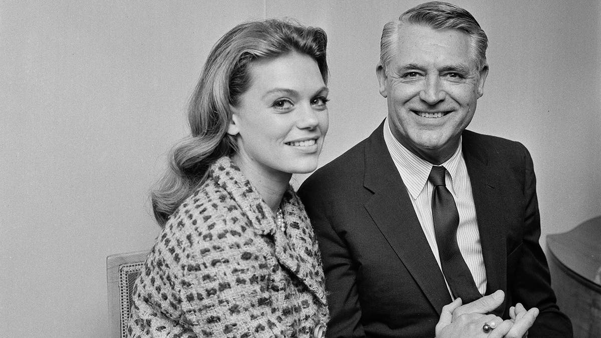 Dyan Cannon and Cary Grant smiling as they hold hands.