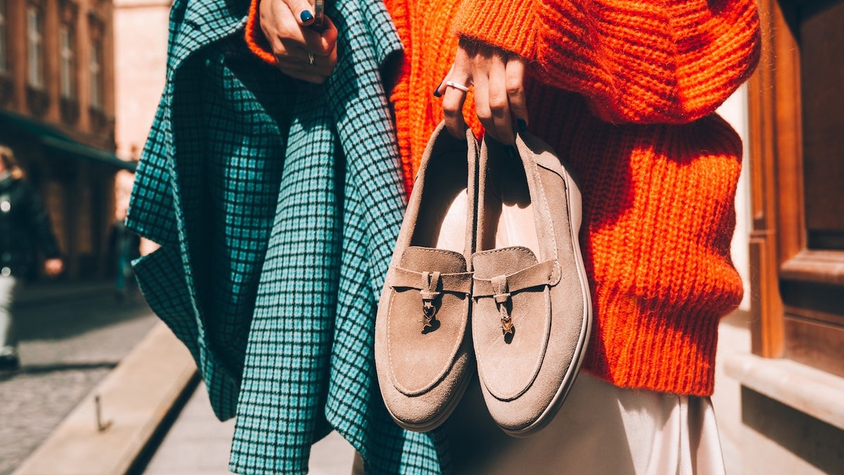 Woman holding beige shoes