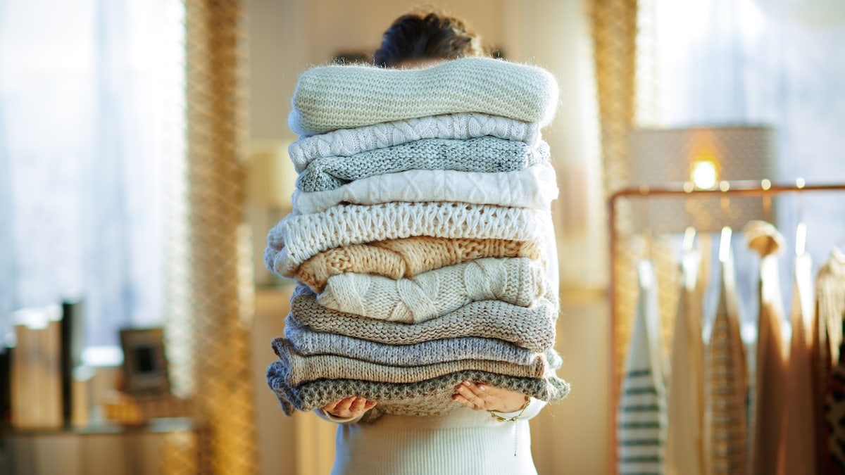 woman holding knit sweaters