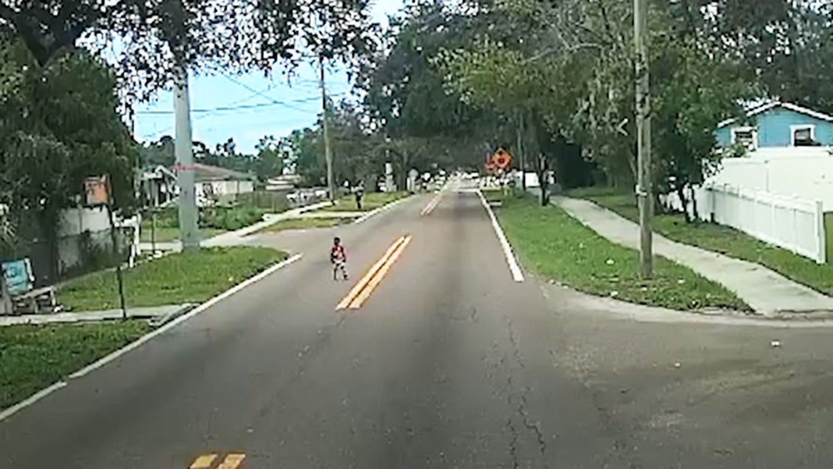 Screenshot from bus security footage showing young boy wandering lost in Tampa street, barefoot and in pajamas.
