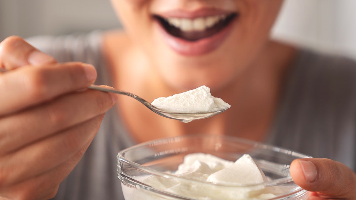 Woman smiling with greek yogurt in spoon
