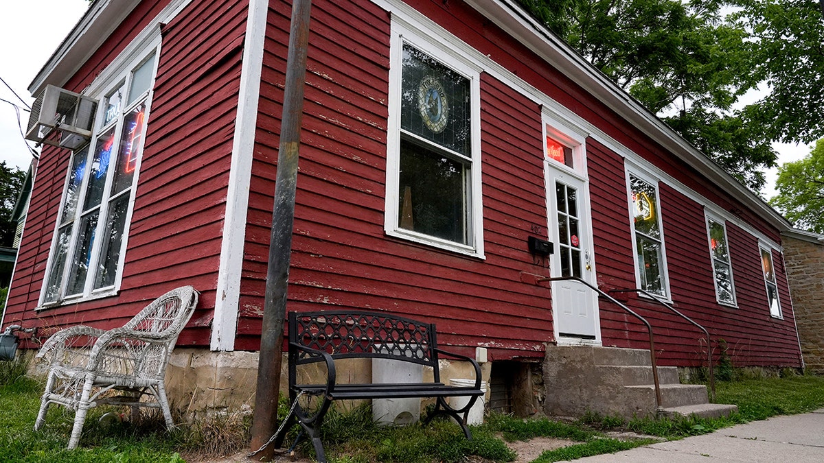 Fox Head Tavern em Iowa City, com seu pequeno exterior vermelho visto de fora, com bancos do lado de fora e placas de bebidas nas janelas.