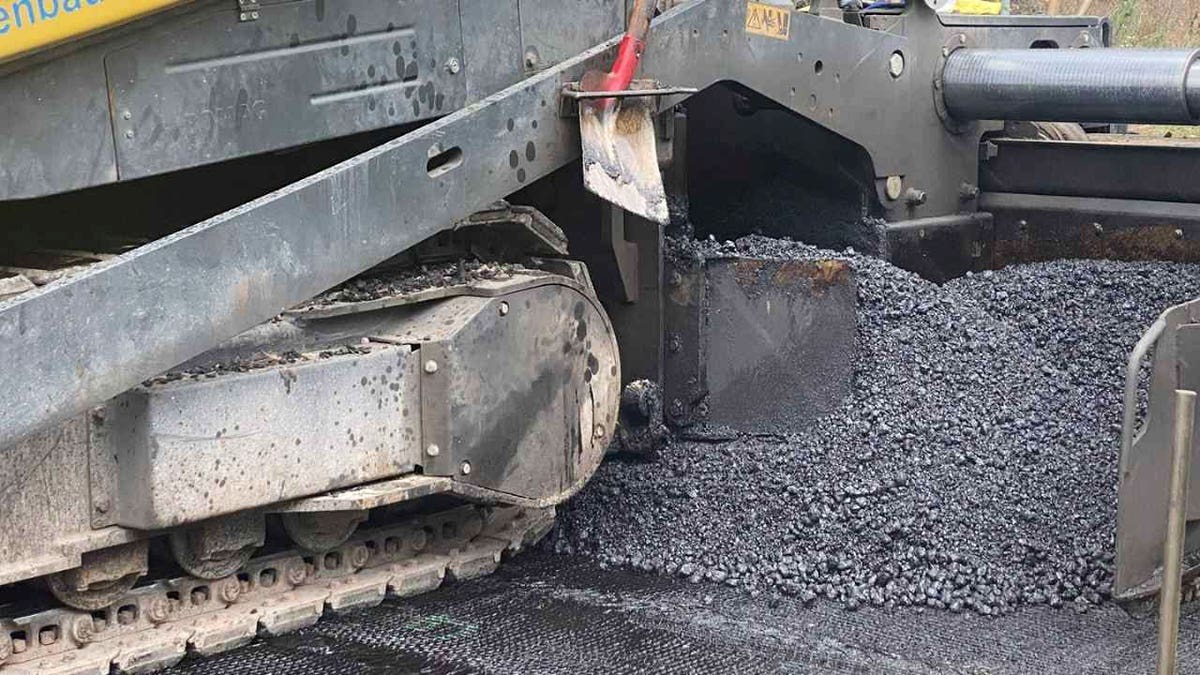 AI sensors in road fabric could prevent costly repairs before damage 1 Road construction machine spreads fresh asphalt as researchers test AI sensors for detecting subsurface damage.