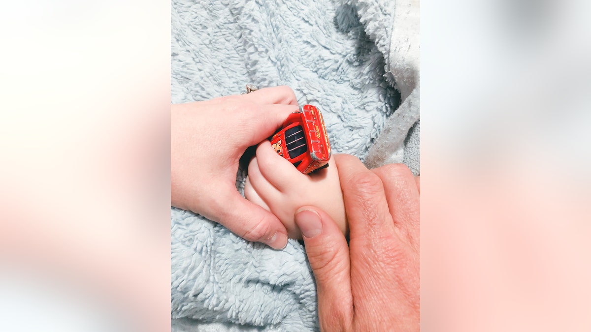 Granger Smith holding onto River's hand as his son holds his favorite toy.