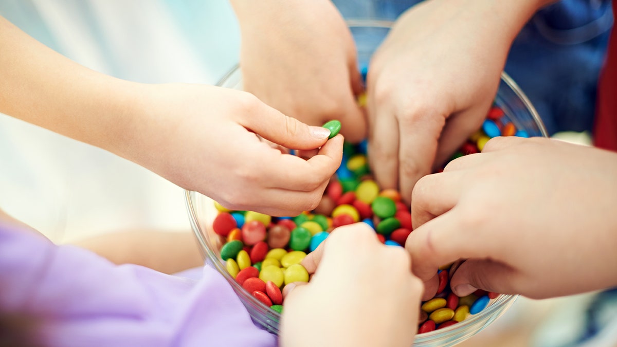 孩子們的手伸進裝滿彩色巧克力糖的玻璃碗裡。