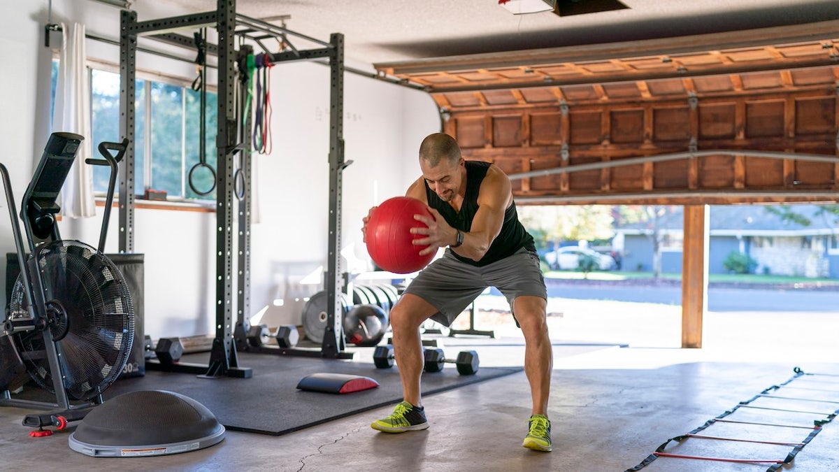 Man using weighted exercise ball while doing workout in home gym