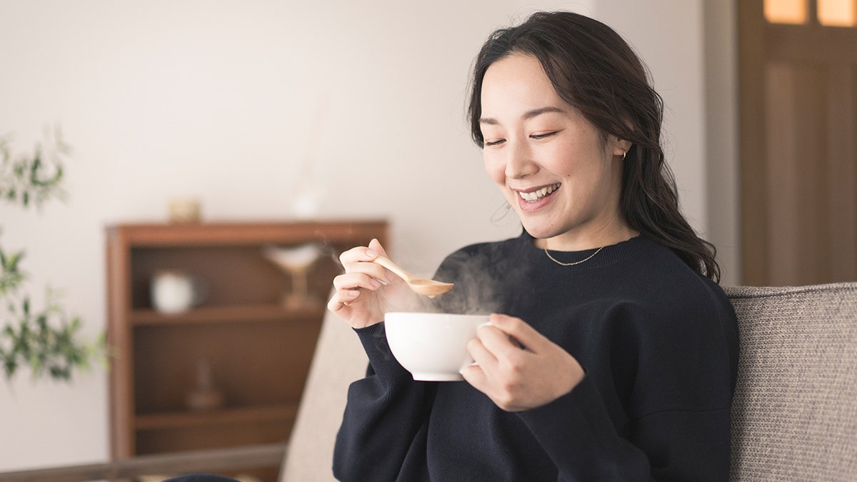 Happy woman drinking soup