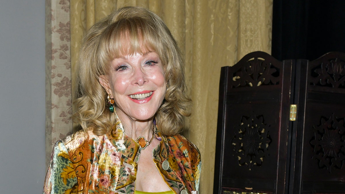 Barbara Eden smiling in a gold suit.
