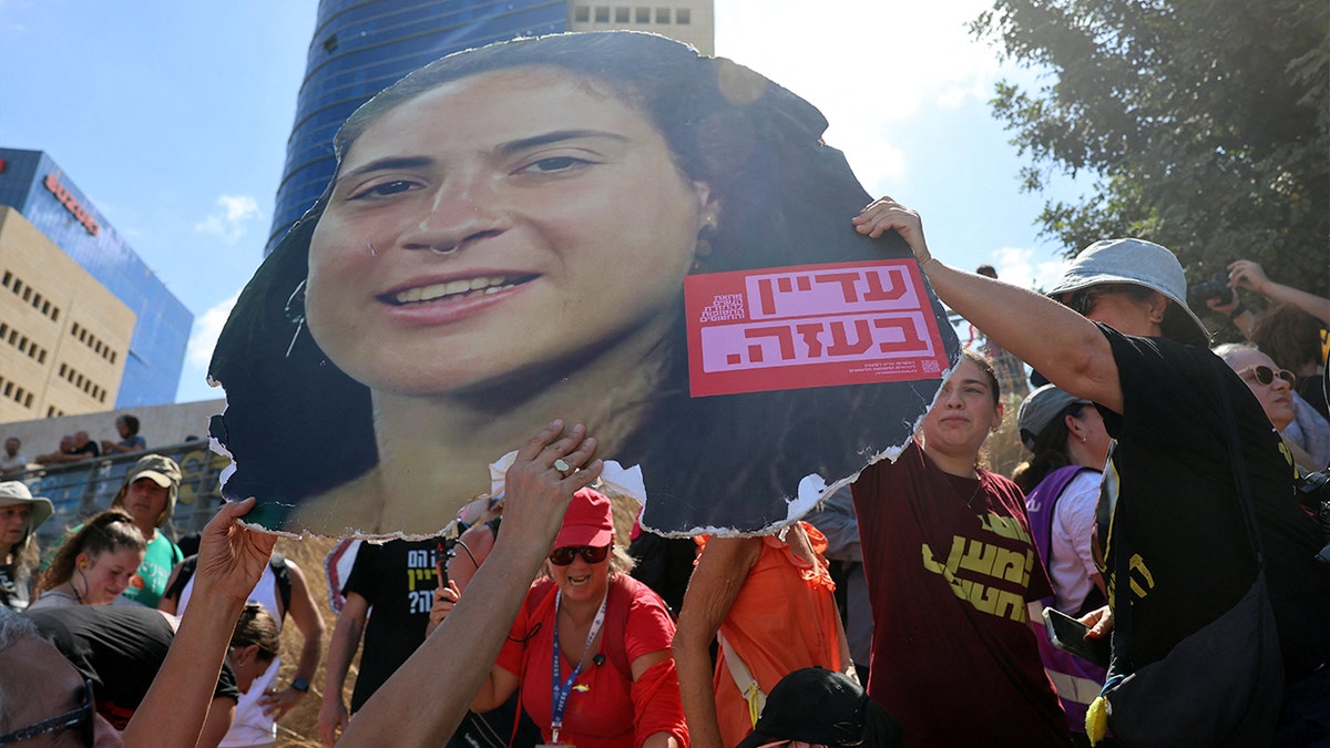 Manifestantes em Israel seguram uma imagem ampliada do rosto do falecido refém Inbar Hayman
