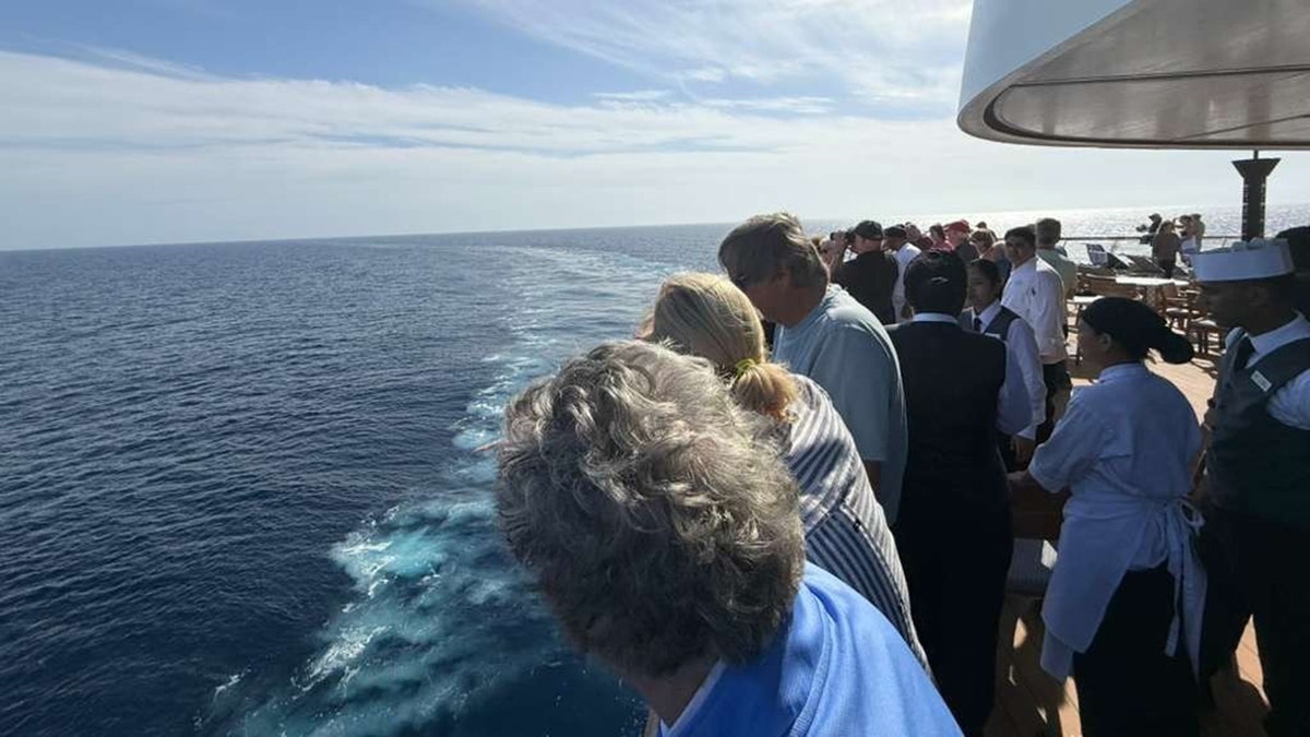 Los pasajeros miran por encima de la barandilla del barco en el mar