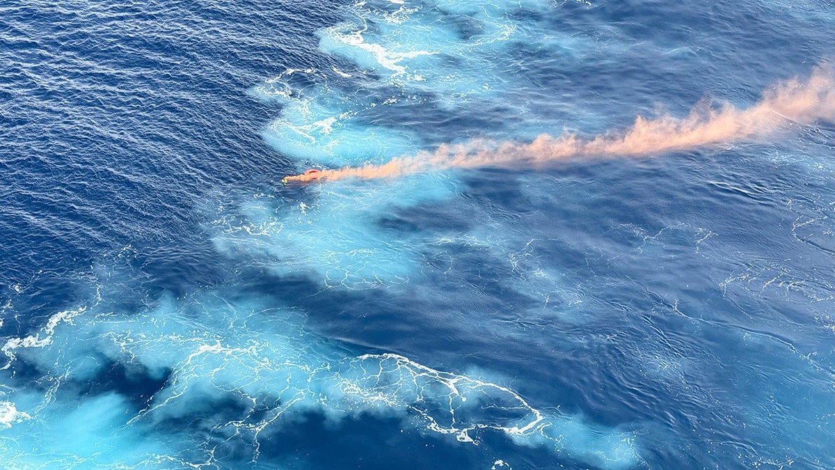 El humo anaranjado flota en el mar azul
