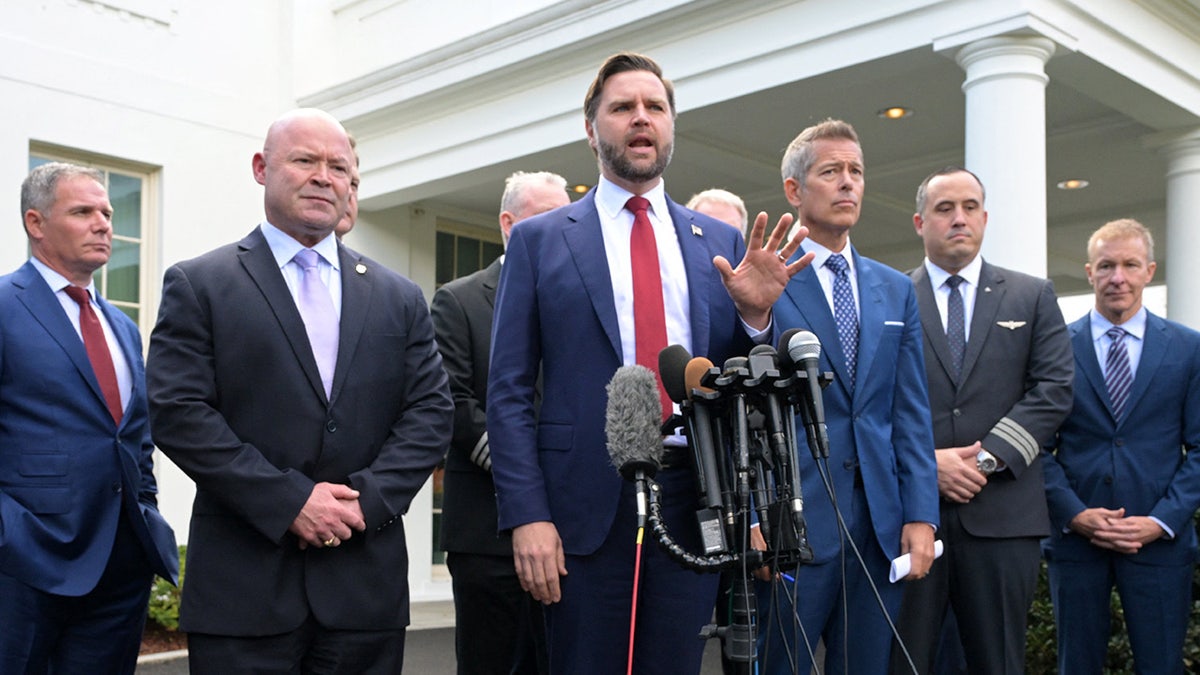 JD Vance stands at microphones while flanked by aviation and union leaders