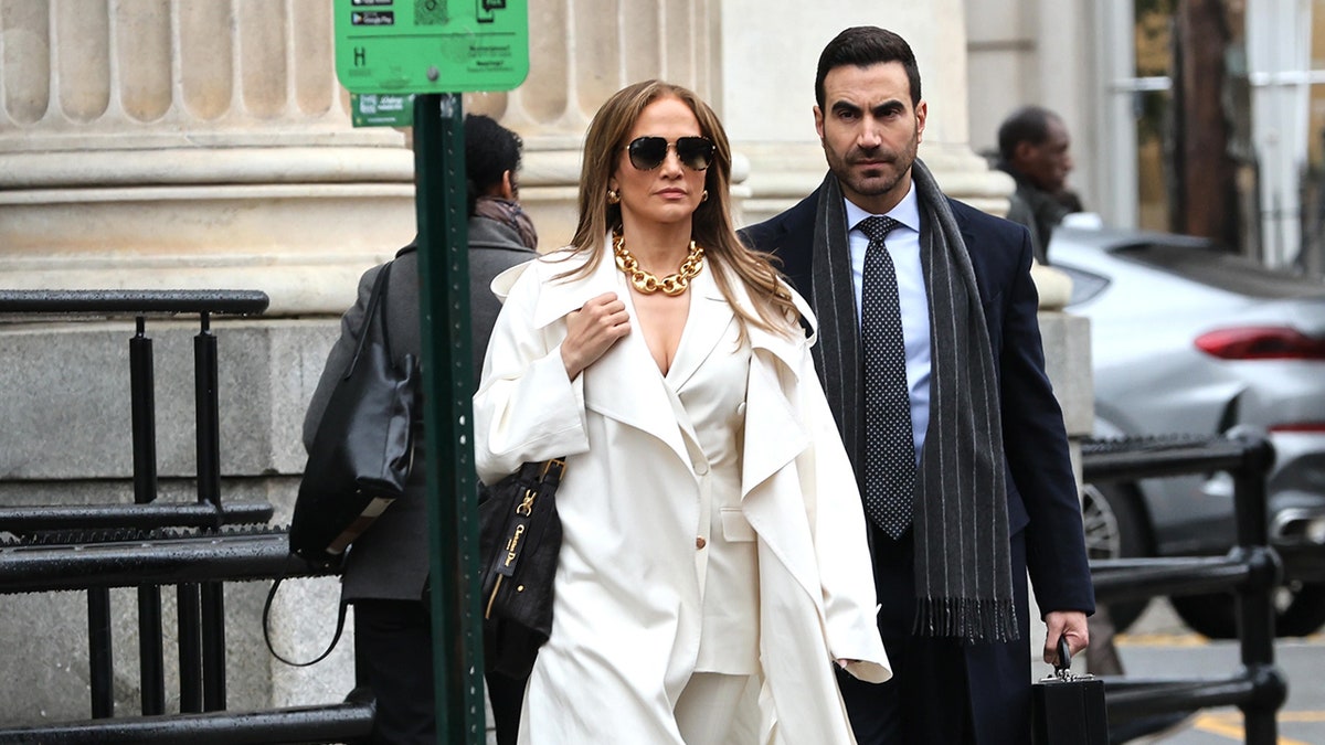 Jennifer Lopez e Brett Goldstein andando por uma rua da cidade, filmando um filme