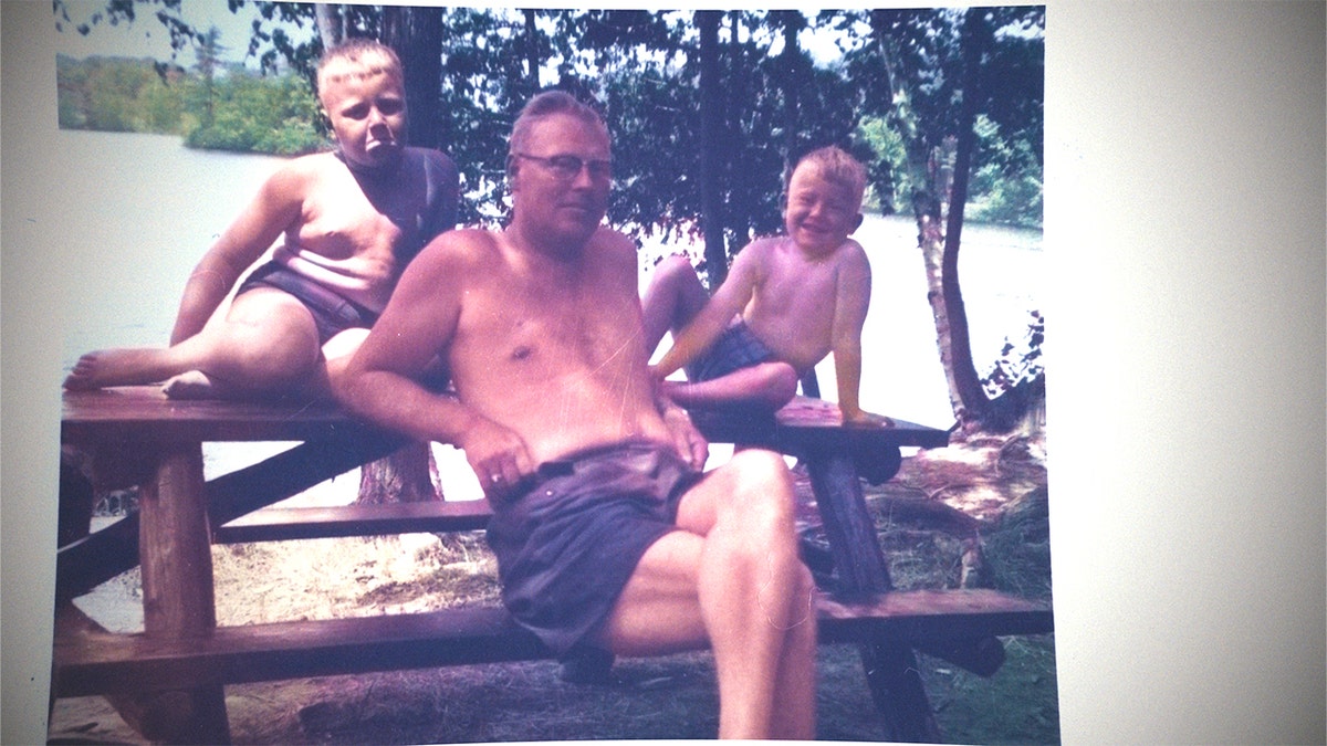 A young John Candy outdoors with his father and brother.