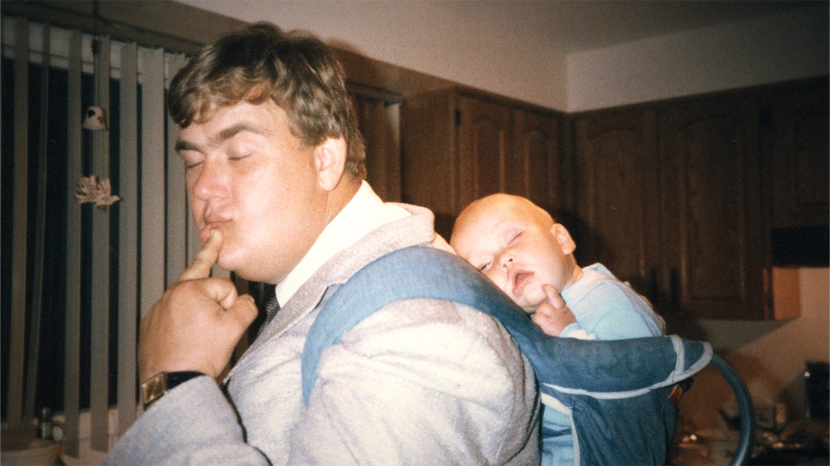 John Candy imitating his sleeping baby on his back.