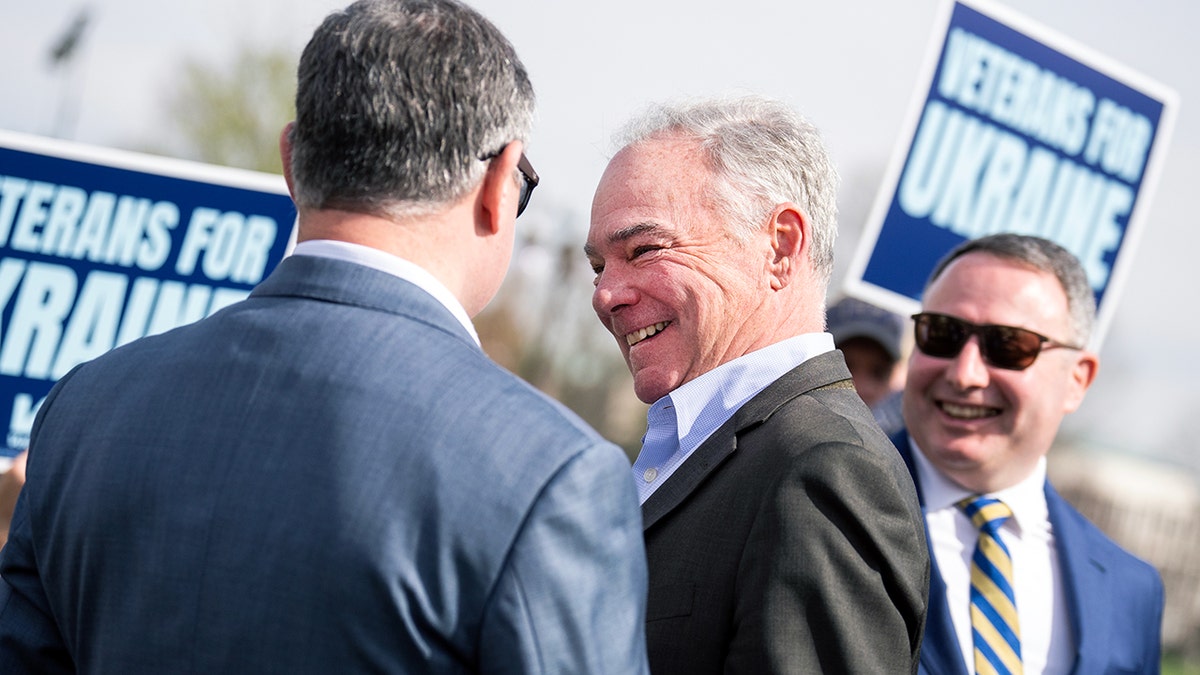 Eugene Vindman and Alexander Vindman speak with Tim Kaine who is smiling
