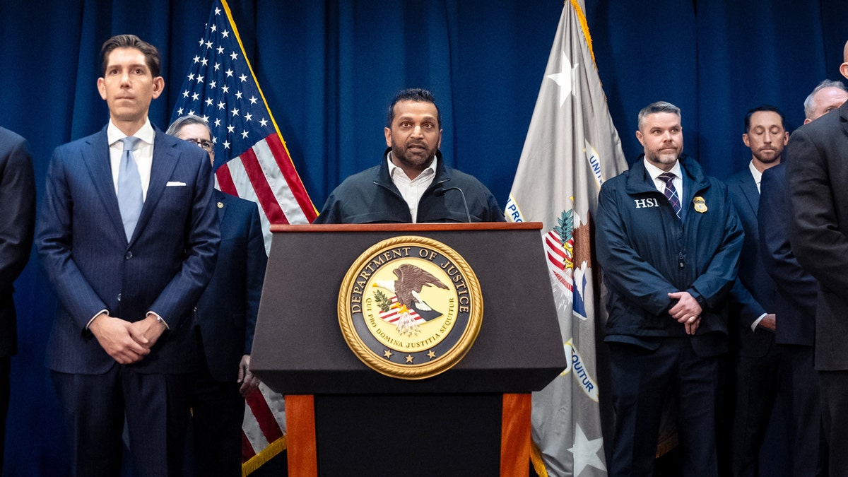 An image of Kash Patel speaking at a podium during a press conference