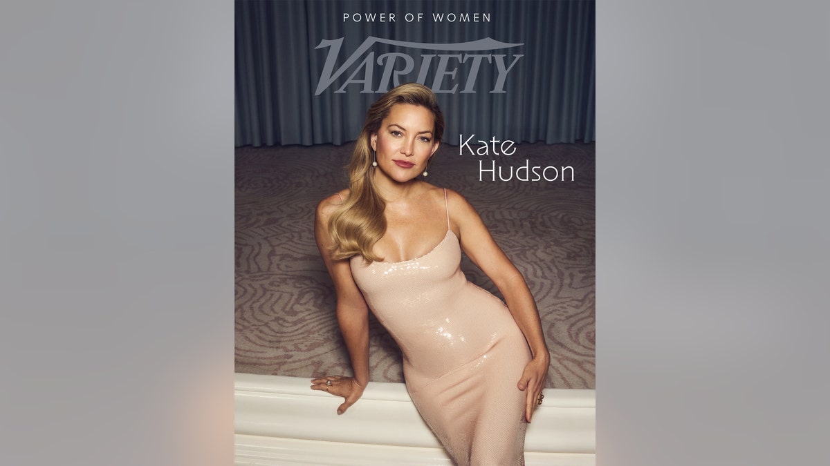 Kate Hudson in a pale pink sequined dress poses gracefully against a neutral backdrop for a magazine cover.