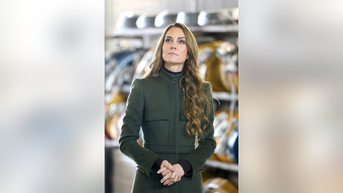 Kate Middleton in a hunter green coat dress looking up.