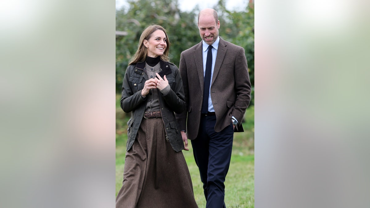 Prince William and Kate Middleton walking together in matching brown attire outdoors.