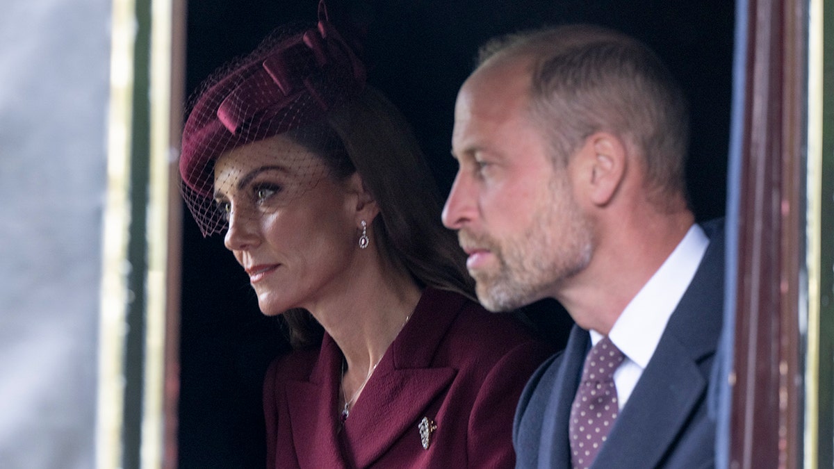 Kate Middleton and Prince William looking serious inside a royal carriage during a state visit.