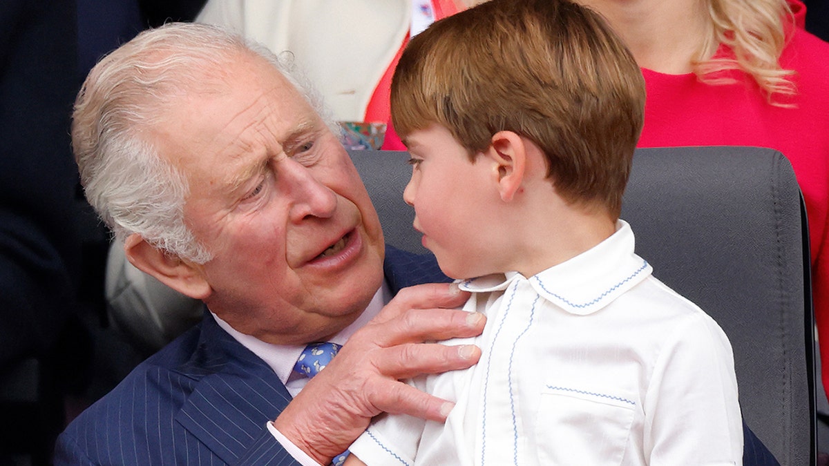 King Charles holding his grandson Prince Louis during an event.