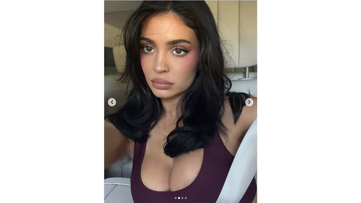 Kylie Jenner takes a selfie in a car wearing a burgundy top with her dark hair styled in loose waves on October 23, 2025.