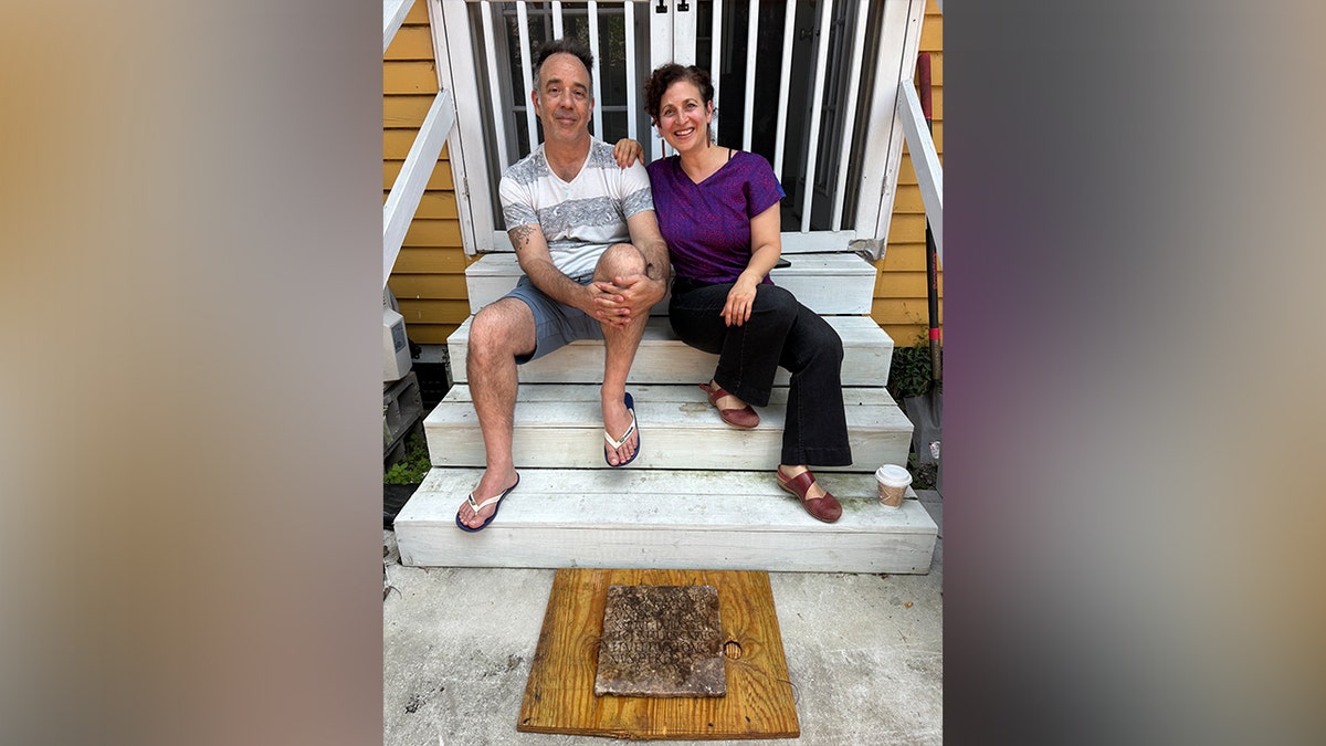 Smiling couple sitting on stoop with ancient stone