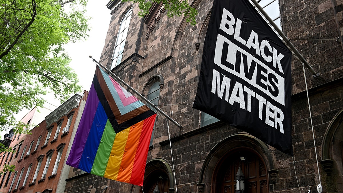 Uma bandeira do Orgulho Progressista e uma bandeira do Black Lives Matter estão penduradas na igreja
