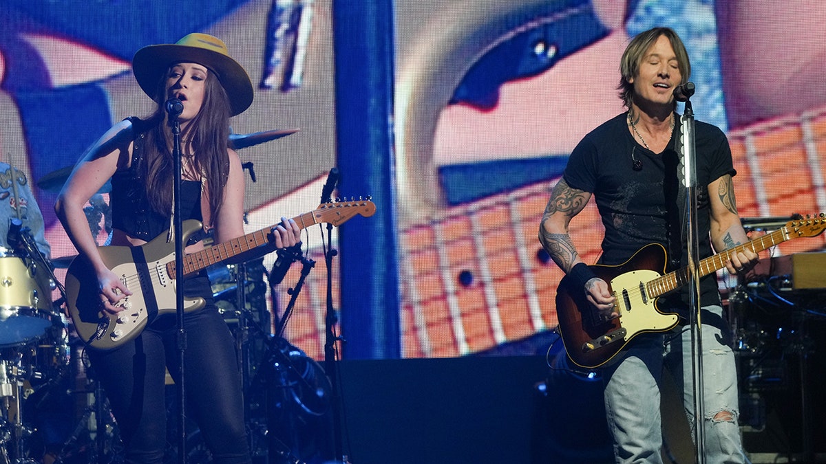 Maggie Baugh and Keith Urban performing on stage at the iHeartCountry Festival in Austin, Texas.