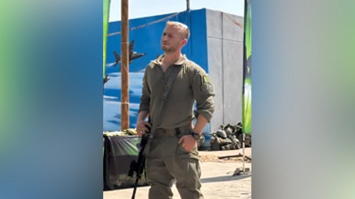Major Yaniv Kula standing with a gun.