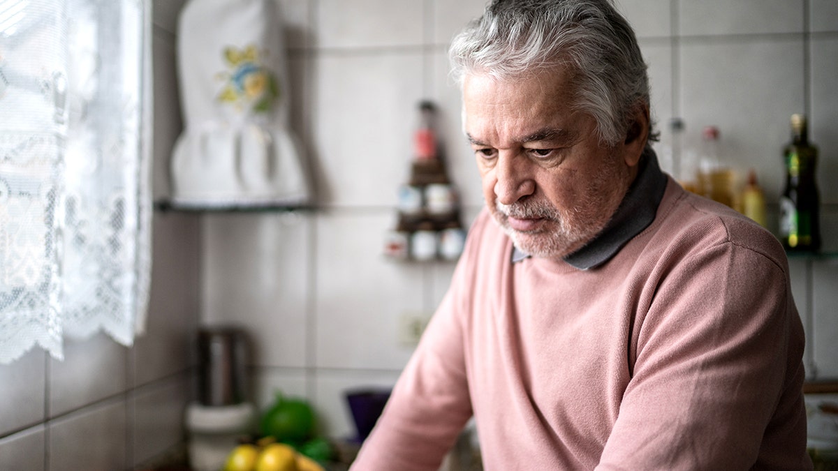 Senior antheral   sitting and holding his caput  successful  symptom  astatine  home