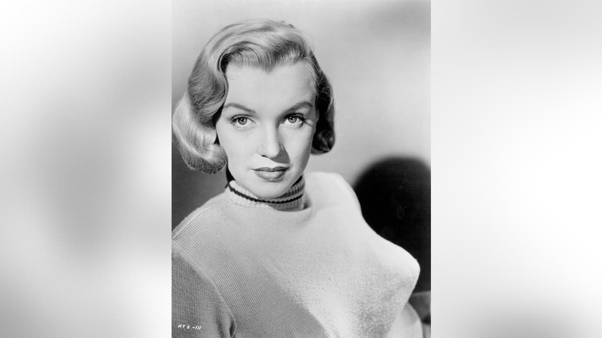 A young Marilyn Monroe posing in a bullet bra and sweater during the 1950s.