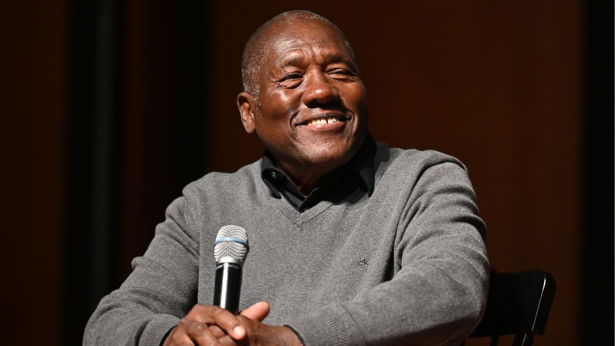 Marvin Dunn speaking into a microphone while seated at an event.