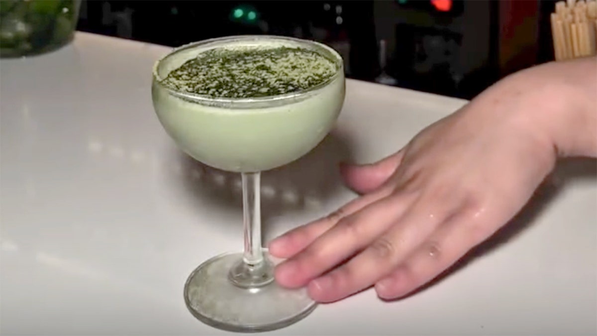A hand touches the bottom of a "Matcha Latte" glass.