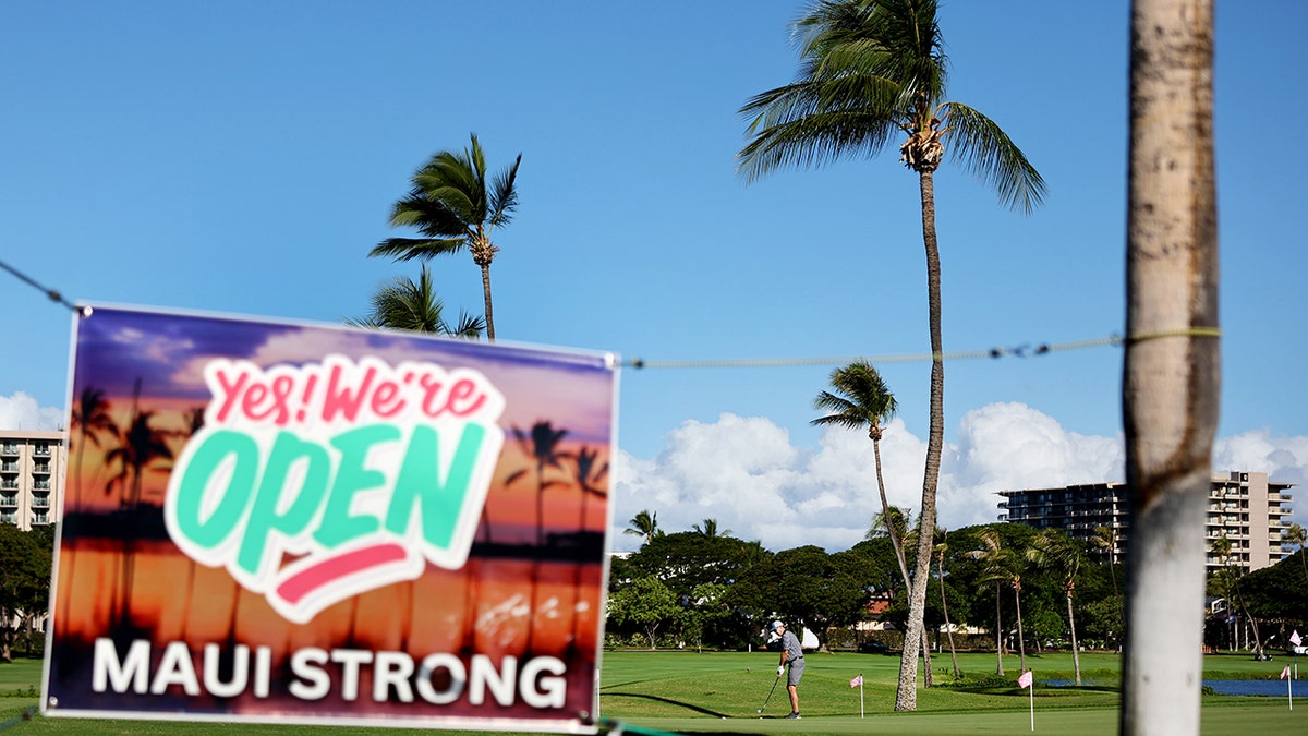 A "yes we're open" sign in Maui, Hawaii, after the wildfires hangs at a golf course.
