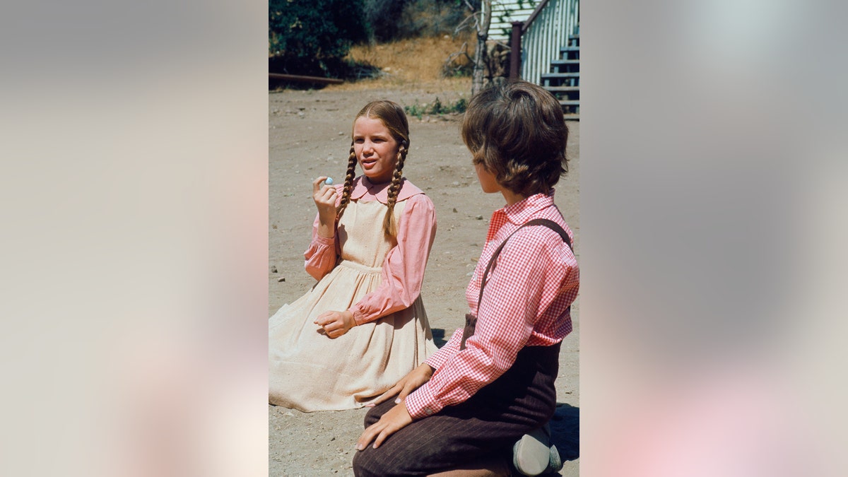 Melissa Gilbert in costume chatting with a young actor filming "Little House on the Prairie."