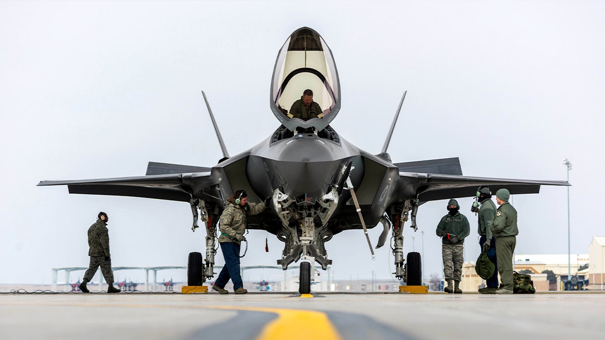 fighter jets park at an air base while the team takes care of the plane