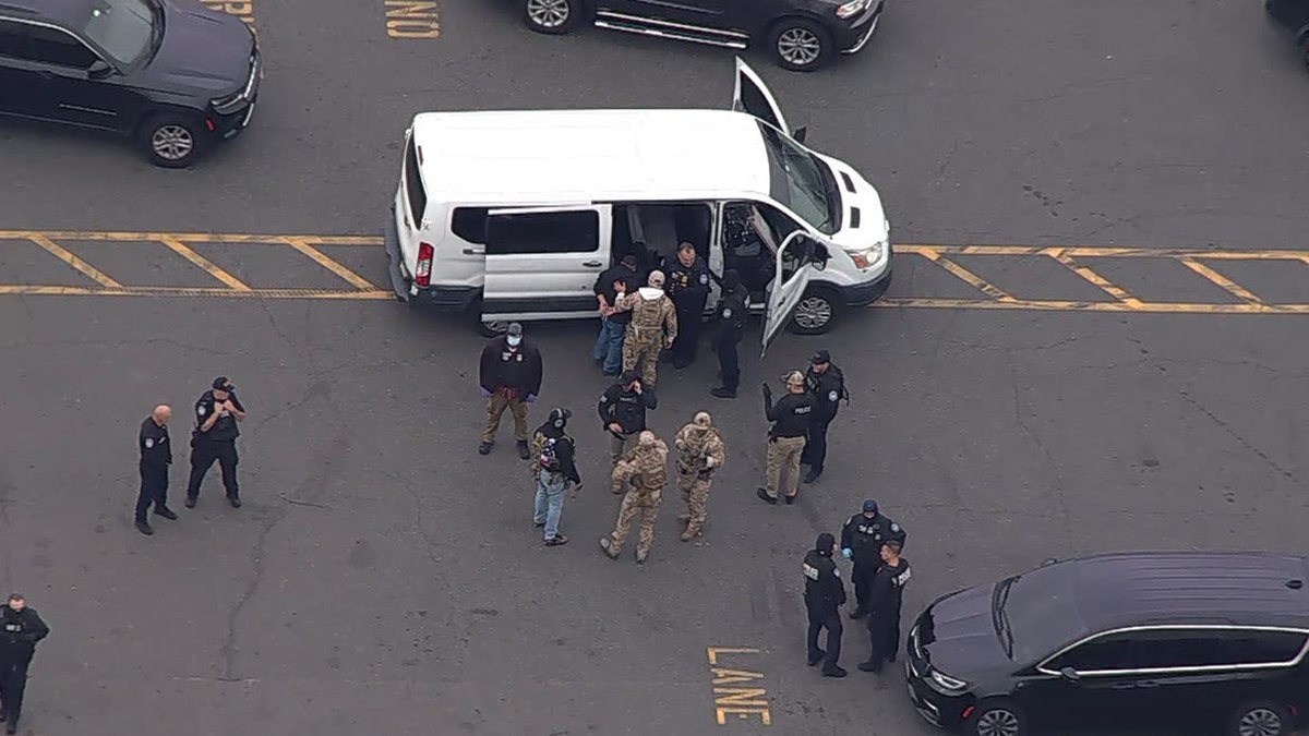 federal officials escort people into white van