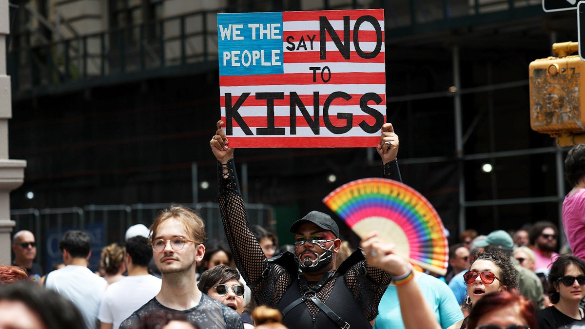 A parade participant carries a poster that reads "Say No To Kings"