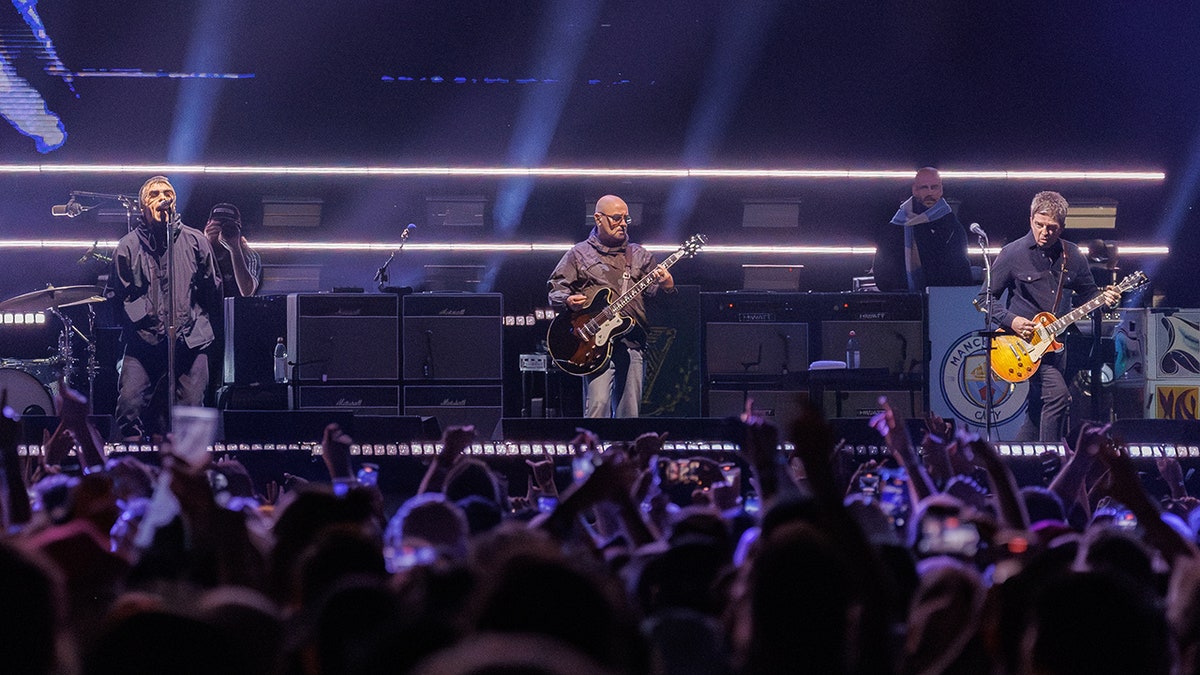 Oasis performing onstage in front of a crowd