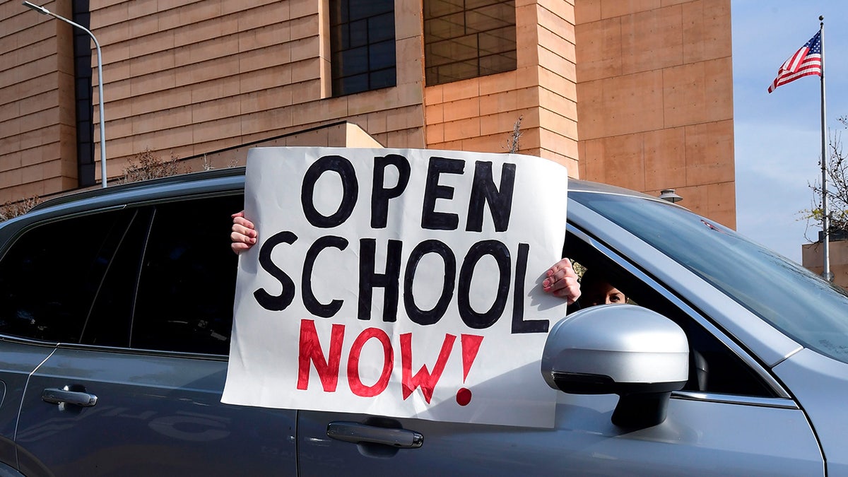 Open School Now sign being displayed outside a car window