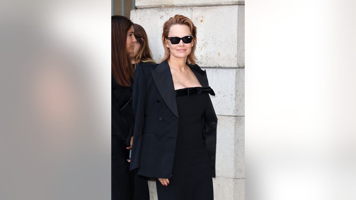 Pamela Anderson with red hair and a black dress at Paris Fashion Week.