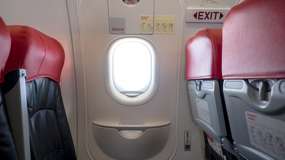Emergency exit window in aircraft cabin.