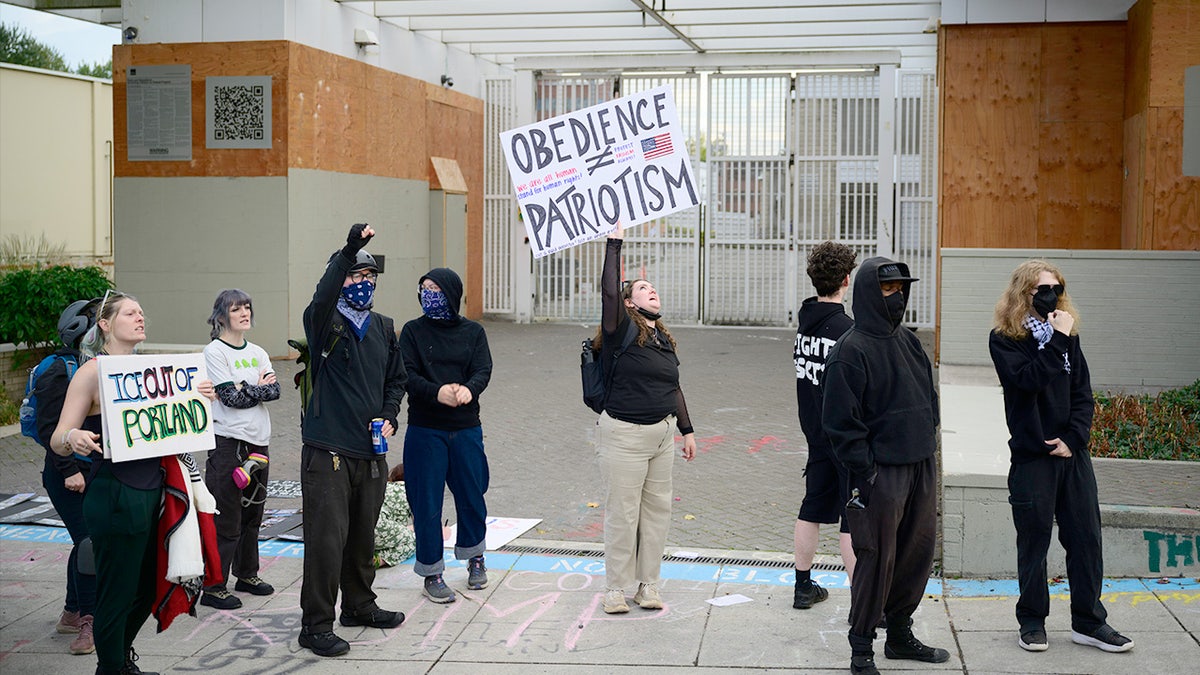 Protesters with signs gather outside the U.S. Immigration and Customs Enforcement building in Portland