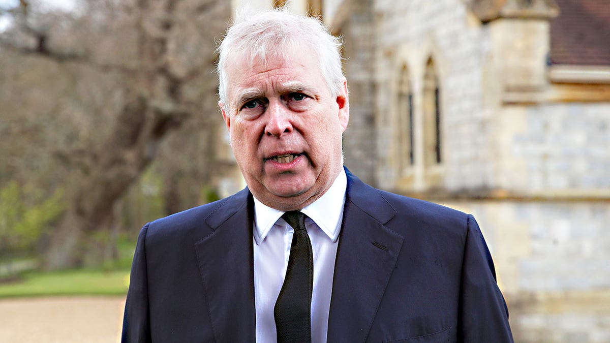 Prince Andrew looking concerned outside a church in a dark suit.
