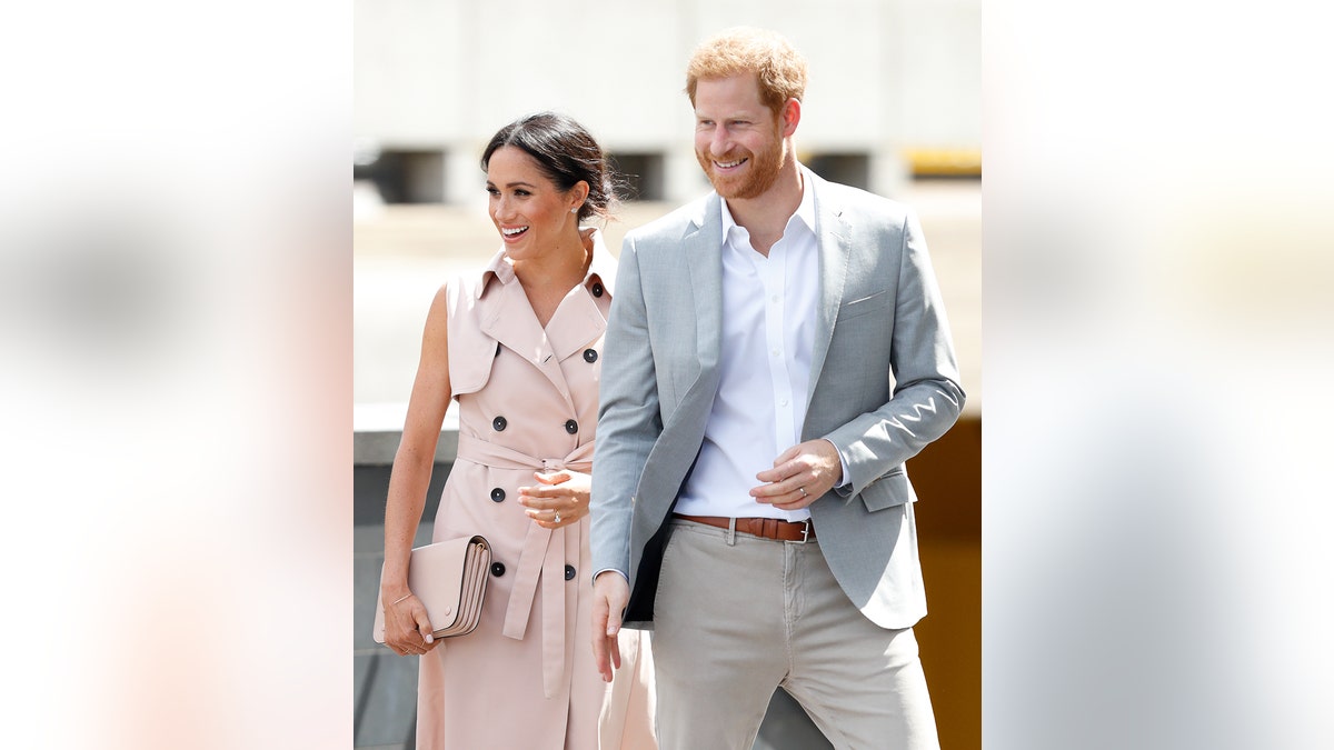 Prince Harry and Meghan Markle smiling and walking alongside each other during a royal engagement.