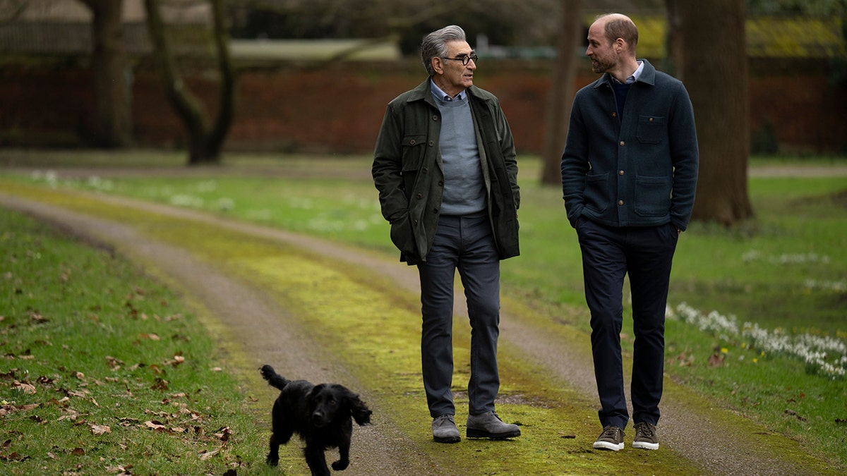Prince William and Eugene Levy walking outside of Windsor Castle as the royal's dog runs ahead.