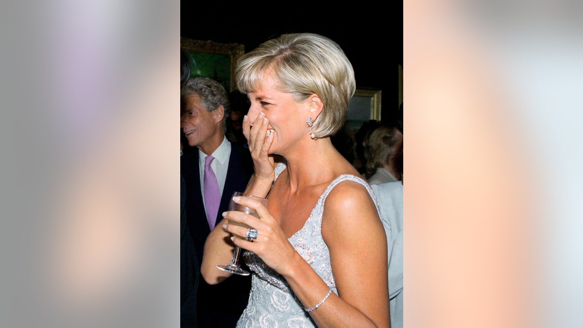 Princess Diana giggling while holding a glass.