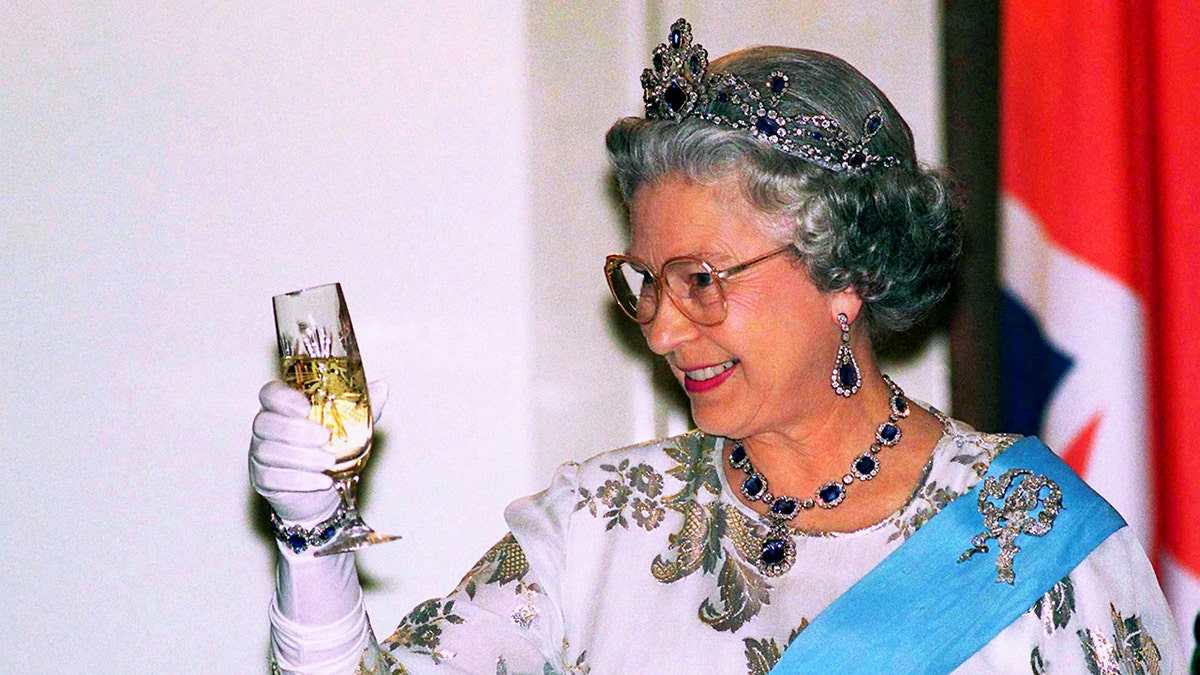 Queen Elizabeth giving a toast wearing her jewels.